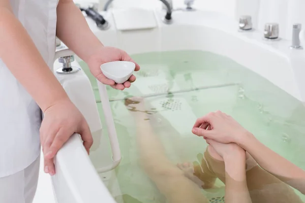 Ritagliato colpo di assistente salone spa e cliente in vasca idromassaggio — Foto stock