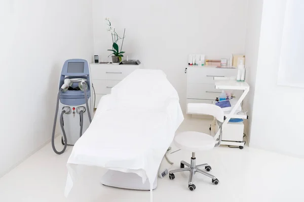 Vista de cerca del aparato de cosmetología y la mesa de masaje vacía en el salón - foto de stock