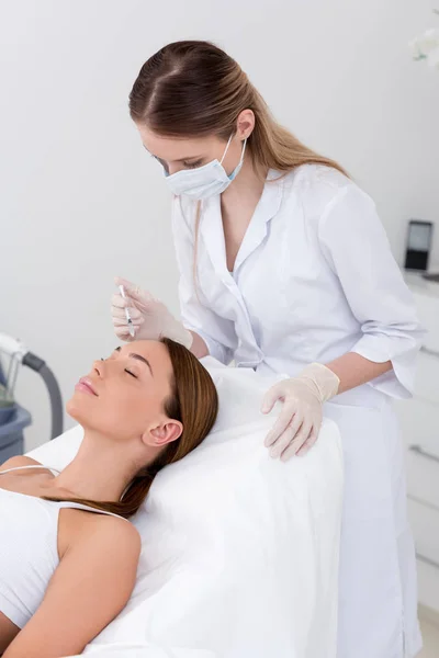 Jovem mulher recebendo injeção de beleza feita pelo cosmetologista no salão — Fotografia de Stock