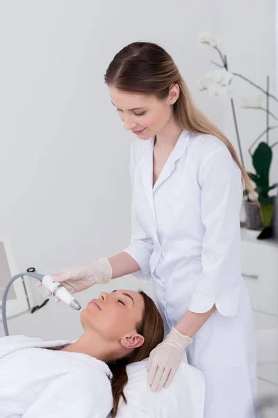 Mujer joven recibiendo tratamiento facial en el salón de cosmetología - foto de stock