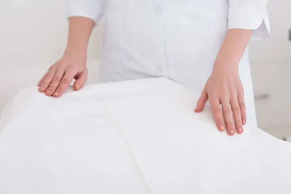 Partial view of cosmetologist in white coat standing near empty massage table in salon — Stock Photo