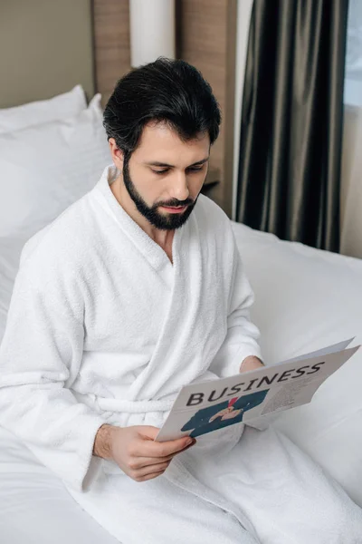 Sério homem de negócios em roupão de banho ler jornal na suíte do hotel — Fotografia de Stock