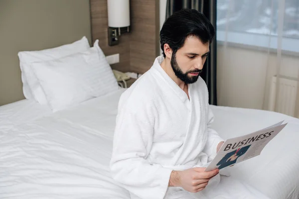 Bel homme d'affaires en peignoir lisant le journal de la suite de l'hôtel — Photo de stock