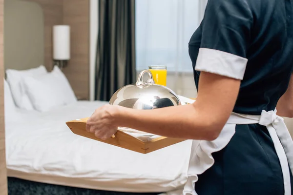 Cropped shot of maid in uniform holding breakfast covered with cloche on tray — Stock Photo