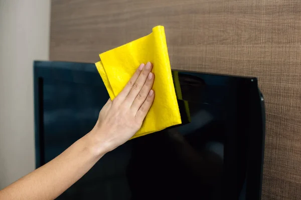 Cropped shot of maid in uniform cleaning tv screen with rag — Stock Photo