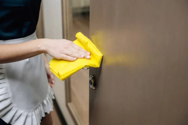 Cropped shot of maid in uniform cleaning hotel suit with rag — Stock Photo