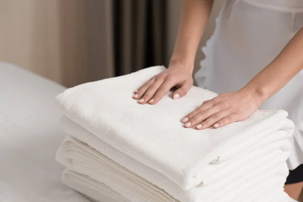 Young beautiful maid in uniform with stack of clean towels — Stock Photo