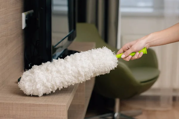 Cropped shot of maid cleaning shelf with duster — Stock Photo