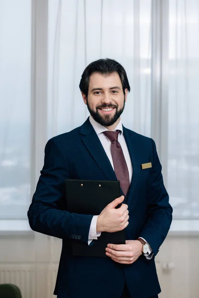 Handsome hotel administrator with clipboard looking at camera — Stock Photo