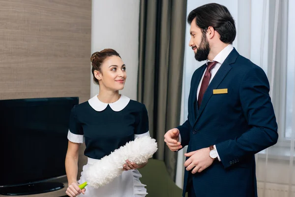 Giovane felice hotel personale di servizio parlando a suite — Foto stock