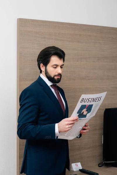 Homme d'affaires barbu lecture de journal à la chambre d'hôtel — Photo de stock