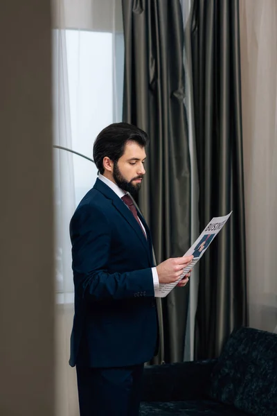 Bel homme d'affaires lisant le journal à la chambre d'hôtel — Photo de stock