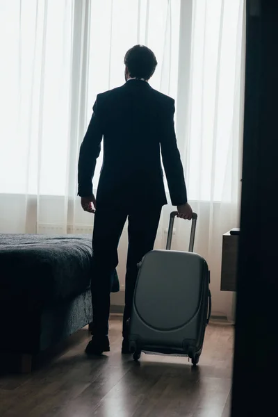 Vue arrière de l'homme d'affaires entrant dans la suite de l'hôtel avec bagages — Photo de stock