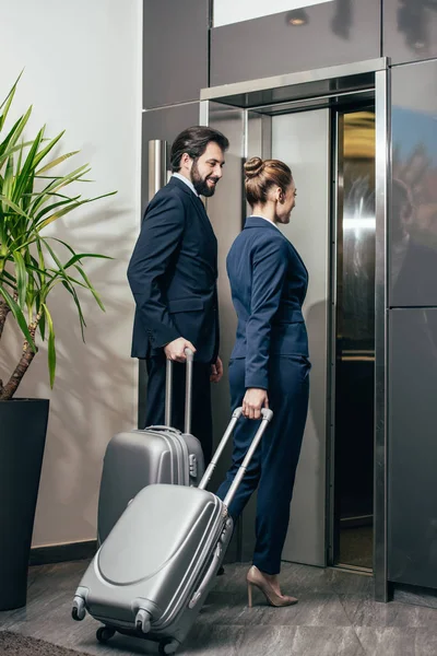Бизнесмены с багажом входят в лифт вместе — стоковое фото