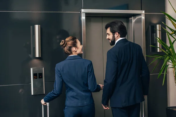 Вид ззаду бізнесменів з багажем, які чекають на ліфт разом — стокове фото