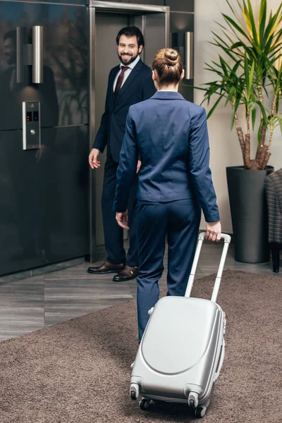 Business people with luggage going on elevator together — Stock Photo