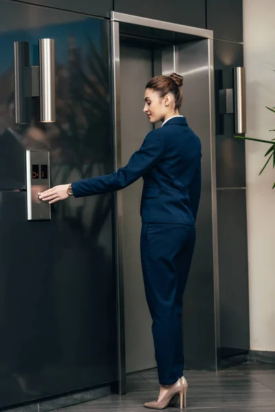 Joven atractiva empresaria pulsando botón de ascensor - foto de stock