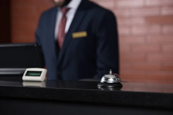 Hotel reception desk with bell and blurred receptionist on background — Stock Photo
