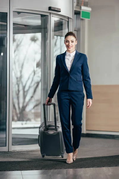 Joven atractiva mujer de negocios saliendo del hotel con el equipaje - foto de stock