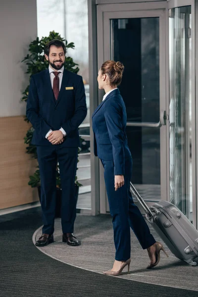 Mujer de negocios saliendo del equipaje del hotel y mirando portero - foto de stock