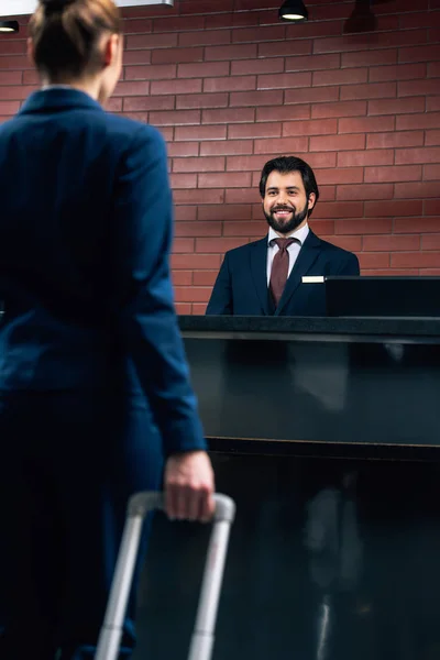 Cropped shot of businesswoman with luggage going at hotel reception counter — Stock Photo