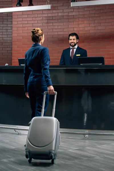 Бізнес-леді з багажем збирається на лічильник готель-прийому — стокове фото