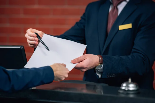 Tiro recortado de la recepcionista del hotel que da contrato al cliente - foto de stock