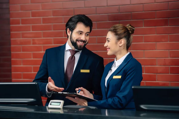 Réceptionnistes souriants de l'hôtel travaillant ensemble au comptoir — Photo de stock
