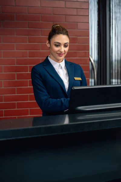 Jovem recepcionista hotel atraente usando computador no local de trabalho — Fotografia de Stock