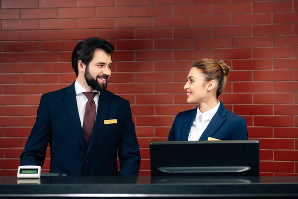Hotel receptionists looking at each other by counter — Stock Photo