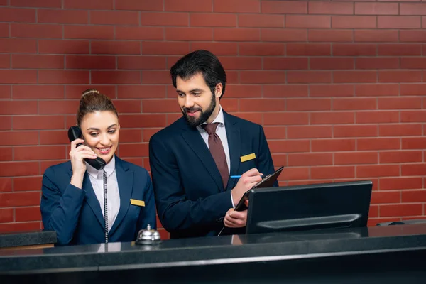Recepcionistas de hotel jóvenes felices en el lugar de trabajo - foto de stock