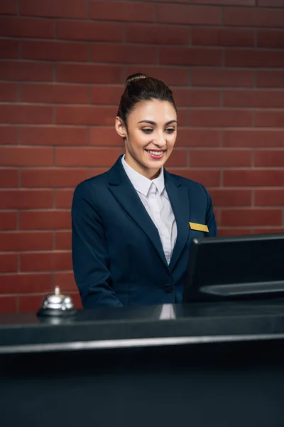 Junge schöne Hotelrezeptionistin blickt am Arbeitsplatz auf den Computerbildschirm — Stockfoto