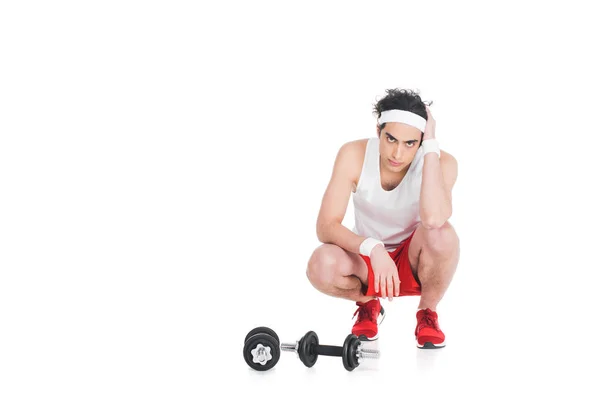 Young skinny man in sportswear sitting near dumbbells — Stock Photo