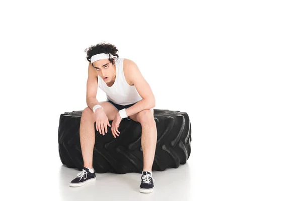 Tired thin sporstman sitting on tire of wheel isolated on white — Stock Photo