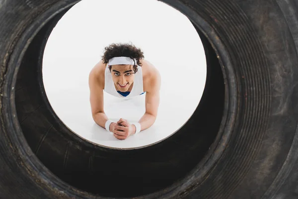 Junger dünner Sportler macht Liegestütze mit Reifen im Vordergrund — Stockfoto