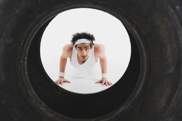 Thin sportsman doing push ups with tire on foreground — Stock Photo