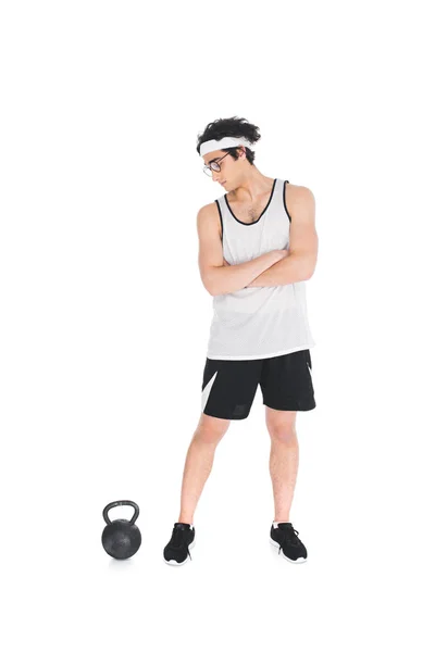Skinny sportsman in eyeglasses looking at kettlebell isolated on white — Stock Photo