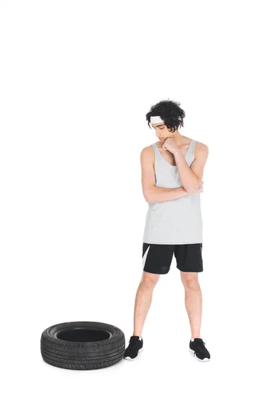 Sportif maigre dans le bandeau regardant le pneu isolé sur blanc — Photo de stock