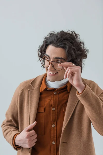 Усміхнений стильний чоловік дивиться за окулярами ізольовано на сірому — стокове фото