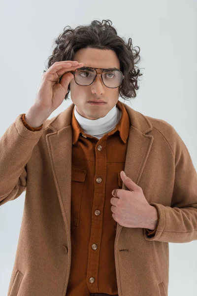Молодий стильний чоловік тримає окуляри ізольовані на сірому — стокове фото