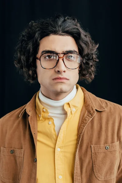 Portrait of male fashion model with curly hair in eyeglasses isolated on black — Stock Photo