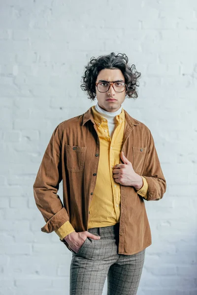 Ritratto di giovane uomo elegante in occhiali davanti al muro di mattoni — Foto stock