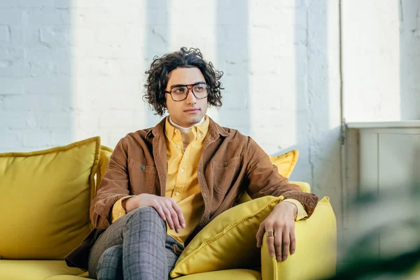 Stilvoller junger Mann mit Brille sitzt auf Couch — Stockfoto