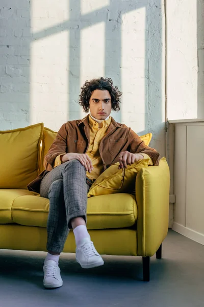 Young stylish man with eyeglasses in hand sitting on couch — Stock Photo