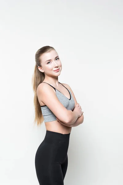 Young woman in sports top with folded arms isolated on white — Stock Photo