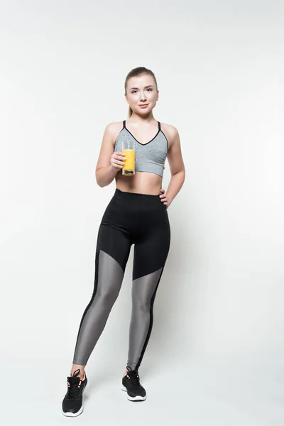 Femme blonde en vêtements de sport tenant verre avec jus isolé sur blanc — Photo de stock