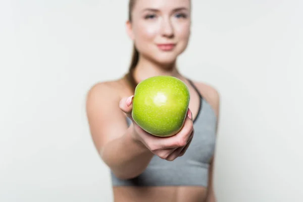 Apple in hand of fitness girl isolated in white — Stock Photo