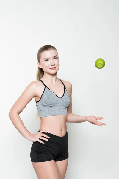 Fit girl playing with apple isolated on white — Stock Photo