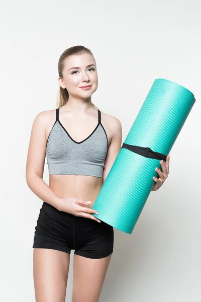 Привлекательная спортивная женщина, держащая коврик для йоги изолированный на белом — стоковое фото