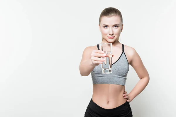 Menina esportiva jovem segurando vidro de água isolada em branco — Fotografia de Stock